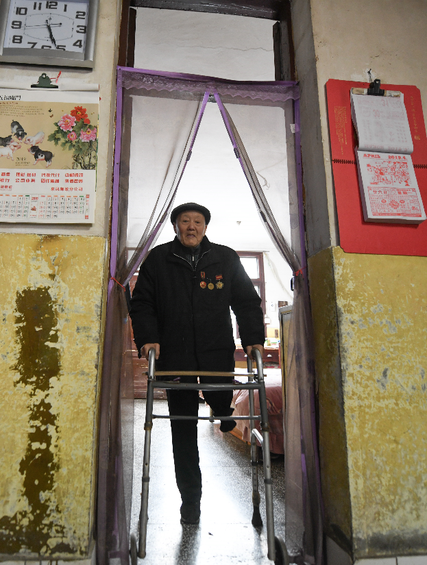 左腿截肢的张富清依靠支撑架在家里活动。