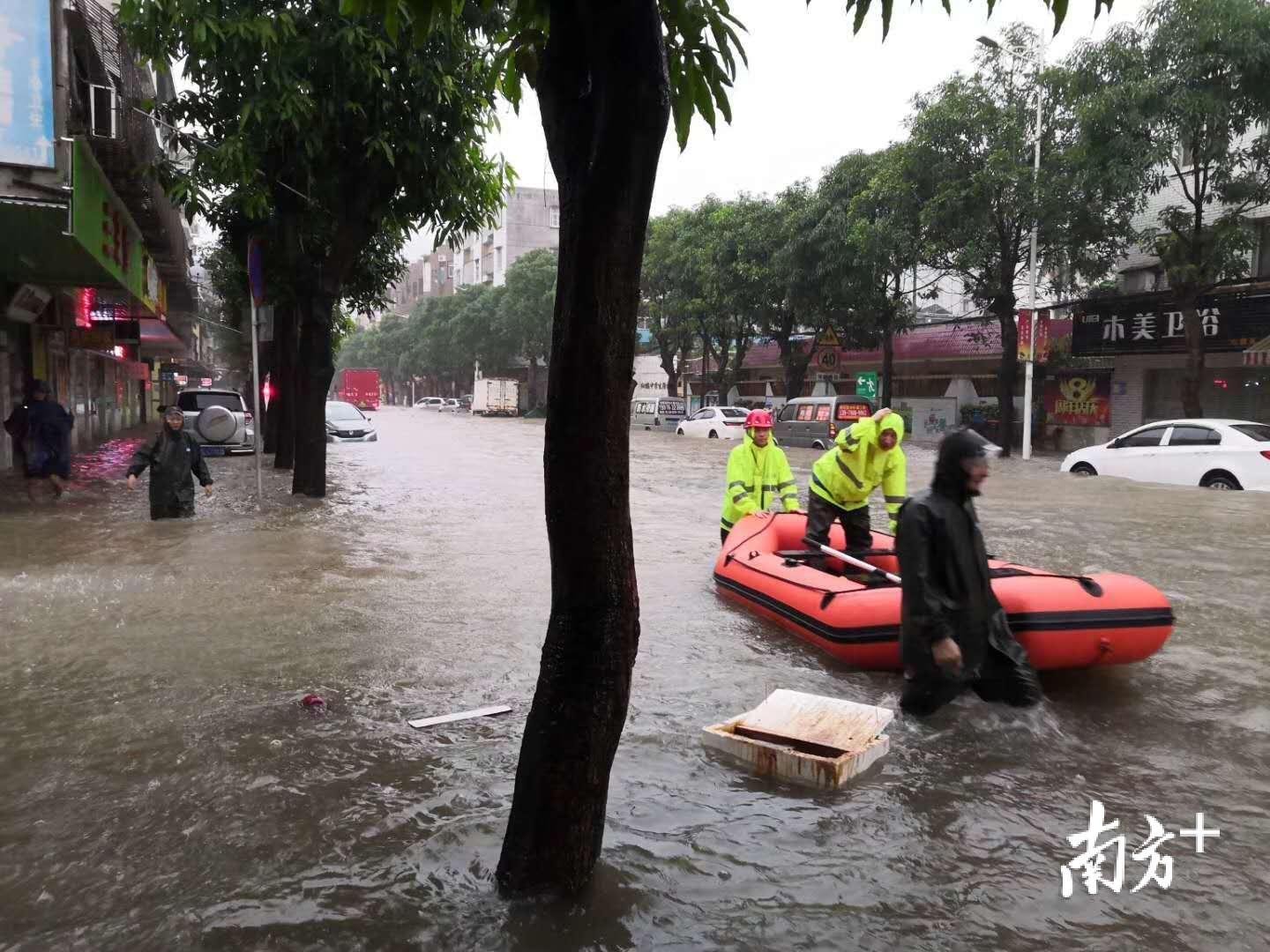 图为工作人员协作熄火汽车走出水浸区域。