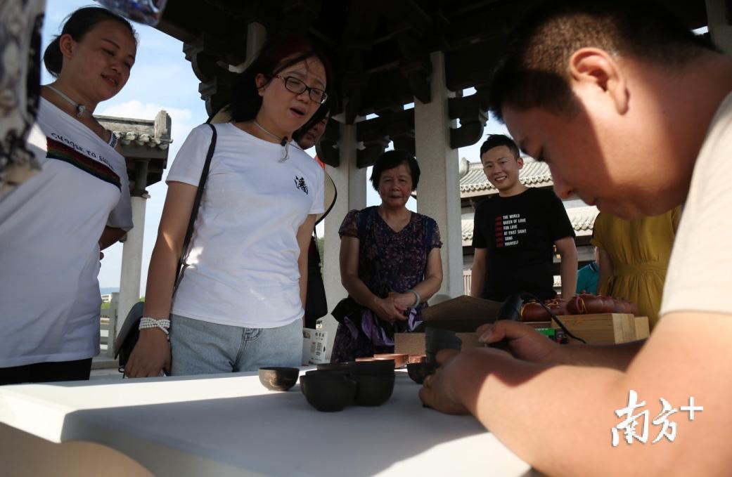 6月8日下午,潮州广济桥,陶刻工艺师吴树荣现场在茶杯上雕刻,其技艺让游客叹为观止。 6月8日下午,潮州广济桥,陶刻工艺师吴树荣现场在茶杯上雕刻,其技艺让游客叹为观止。