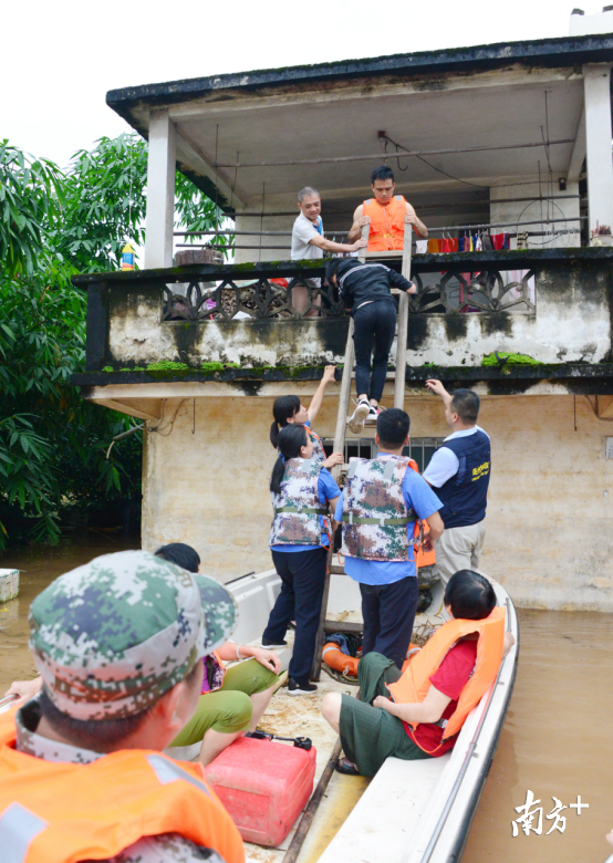 洪水已漫过杨谊连家的2楼。民兵和城监人员在合力帮助被困群众转移至冲锋舟上。全媒体记者黄津 摄