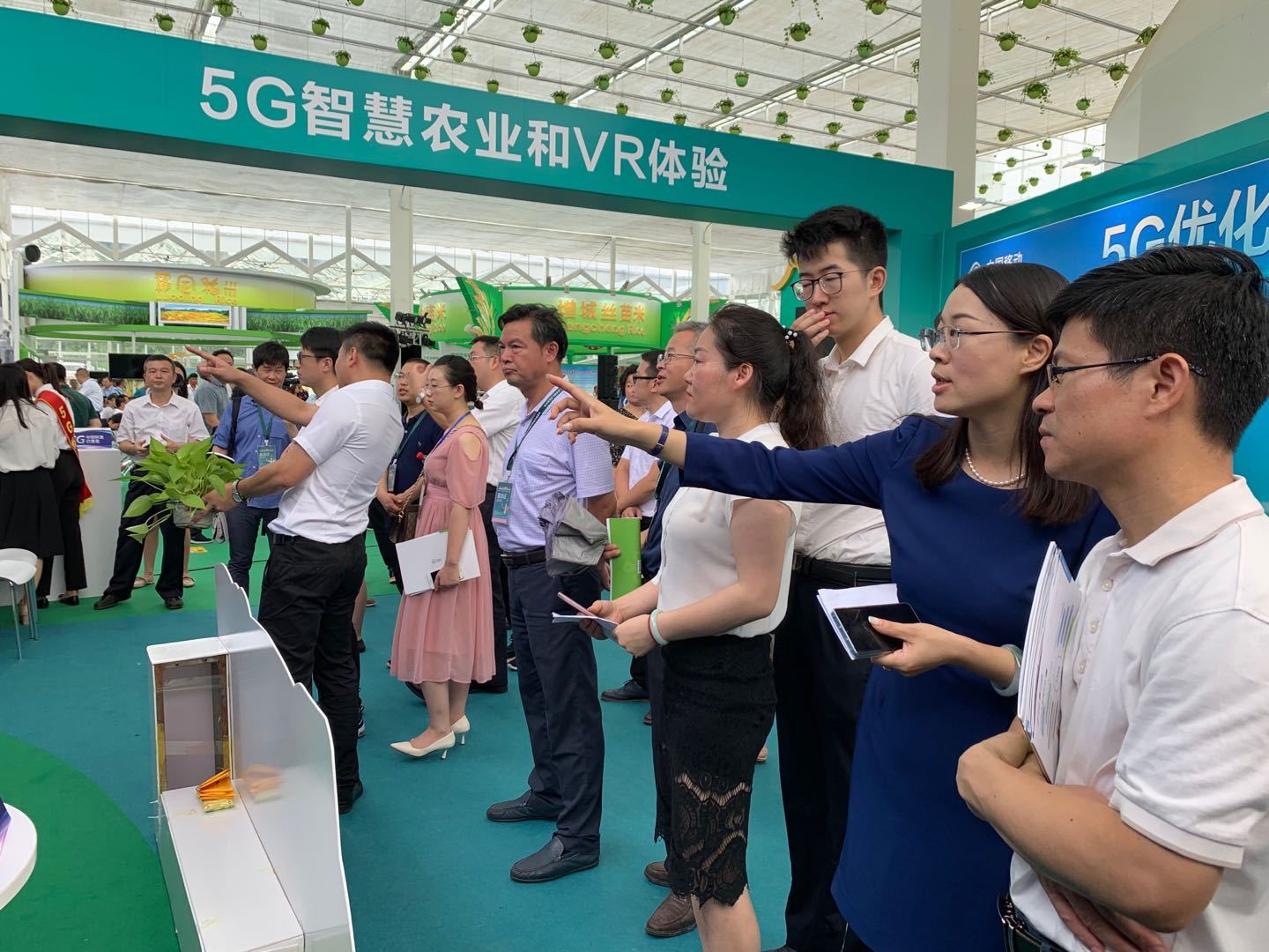 中国联通的5G+现代农业前，观众结合展示屏仔细听取介绍。