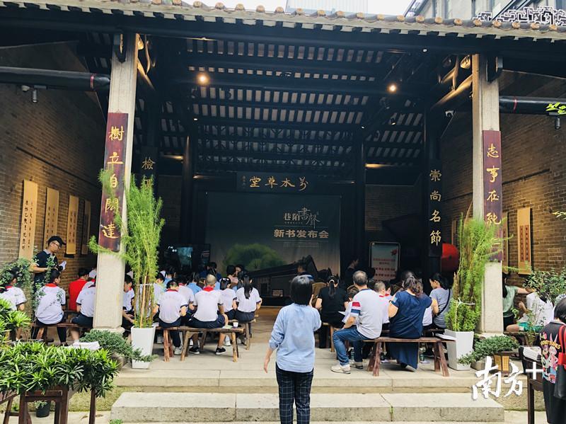 一群戴着鲜艳红领巾的小学生们,整齐地坐成一排,正认真地听越秀古书院