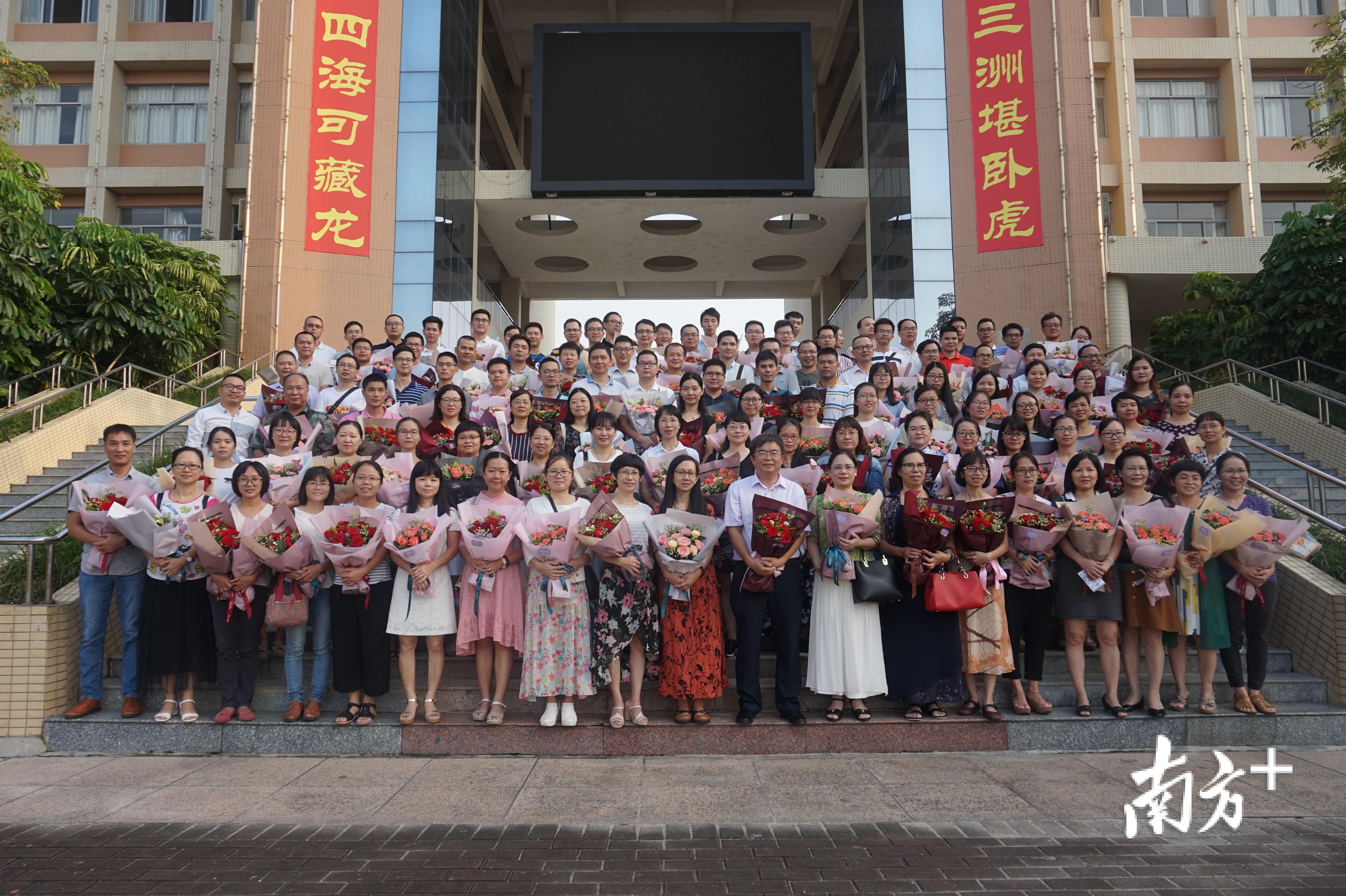 高三全体老师手持学生赠送的鲜花合影。