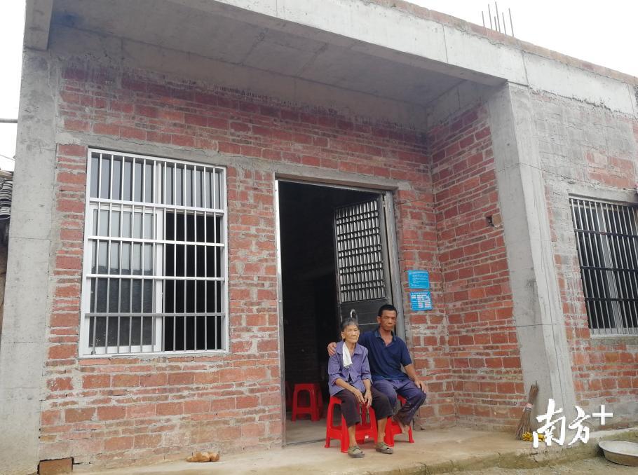 杨进全和母亲坐在新房前。 杨进全和母亲坐在新房前。