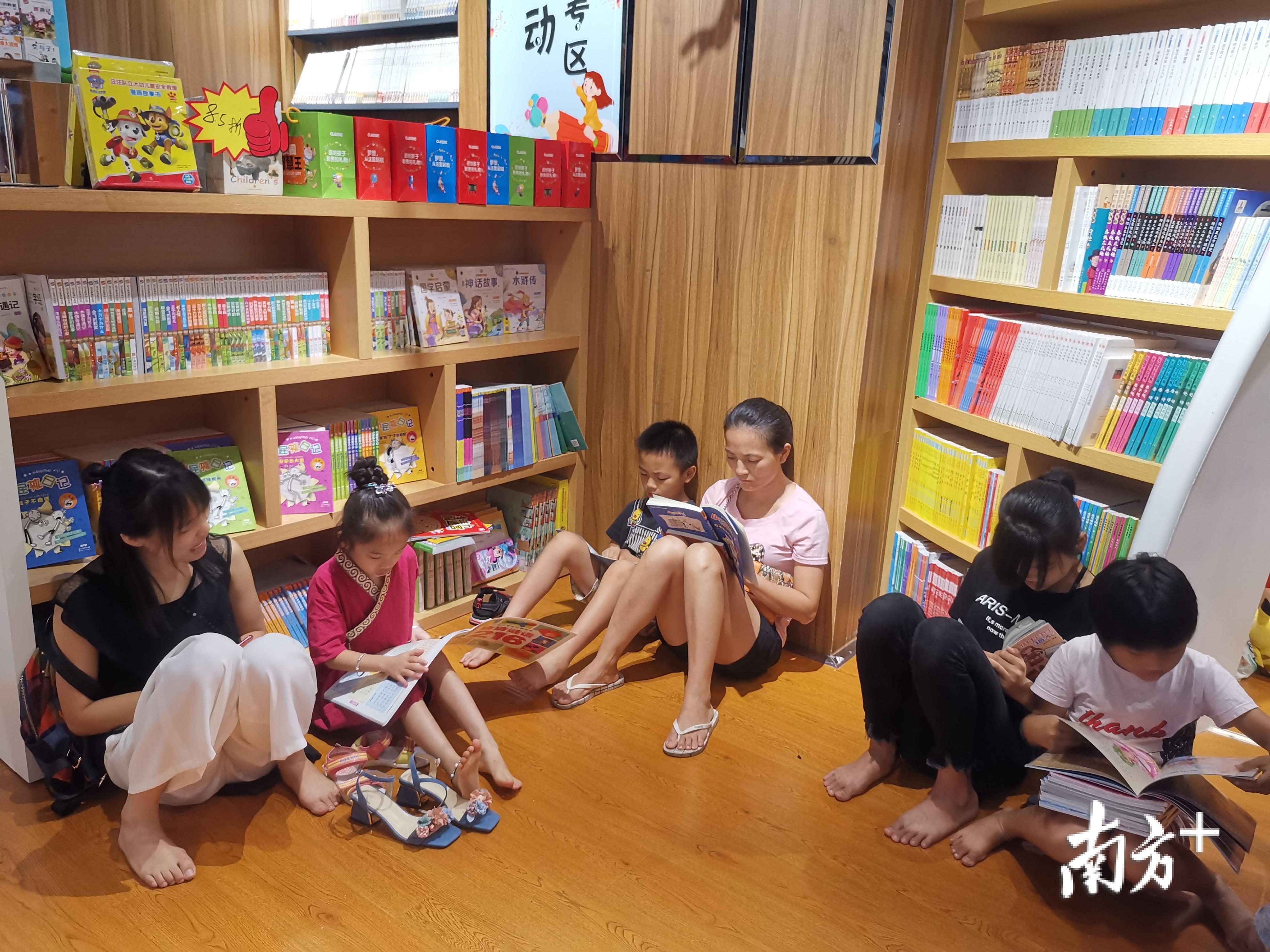 3位大人带着孩子坐在书店一角,引导,陪伴孩子阅读.