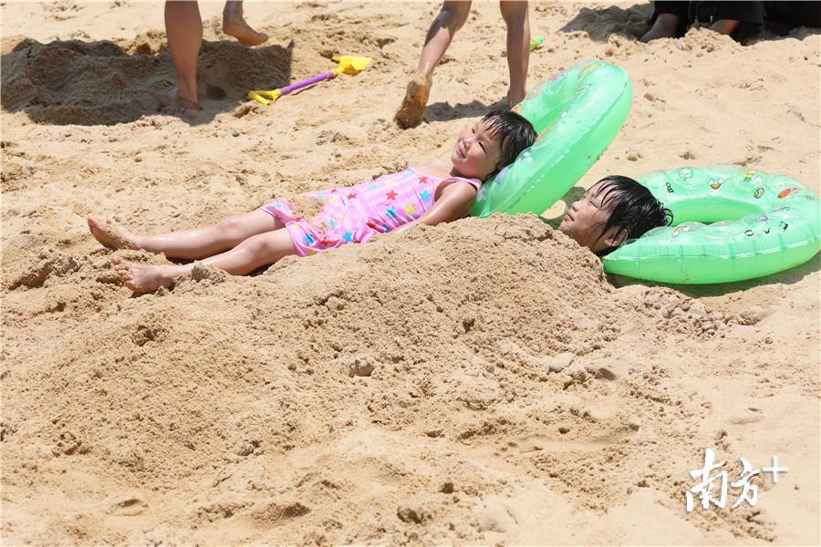 两个小女孩躺在沙滩上,尽情享受阳光浴.