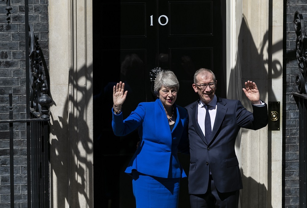 7月24日，在英国伦敦，英国首相特雷莎·梅（左）在发表告别演说后，与丈夫在唐宁街10号首相府前挥手致意。新华社发