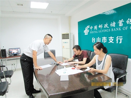 在银行工作人员的帮助下,彭伟勇办理贷款相关手续.邮储银行供图