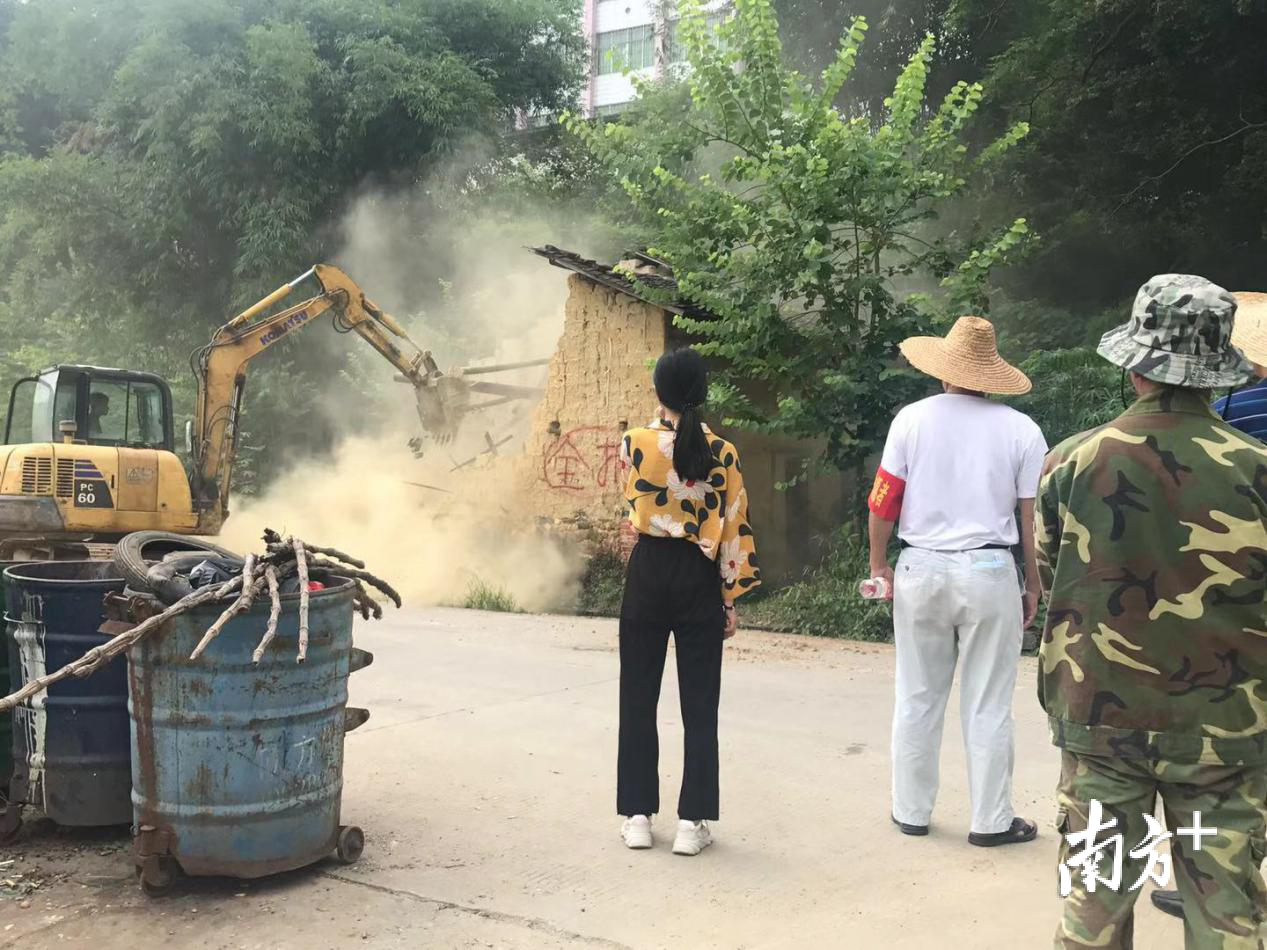 大学生梁文冬在破旧泥砖房清拆行动现场。