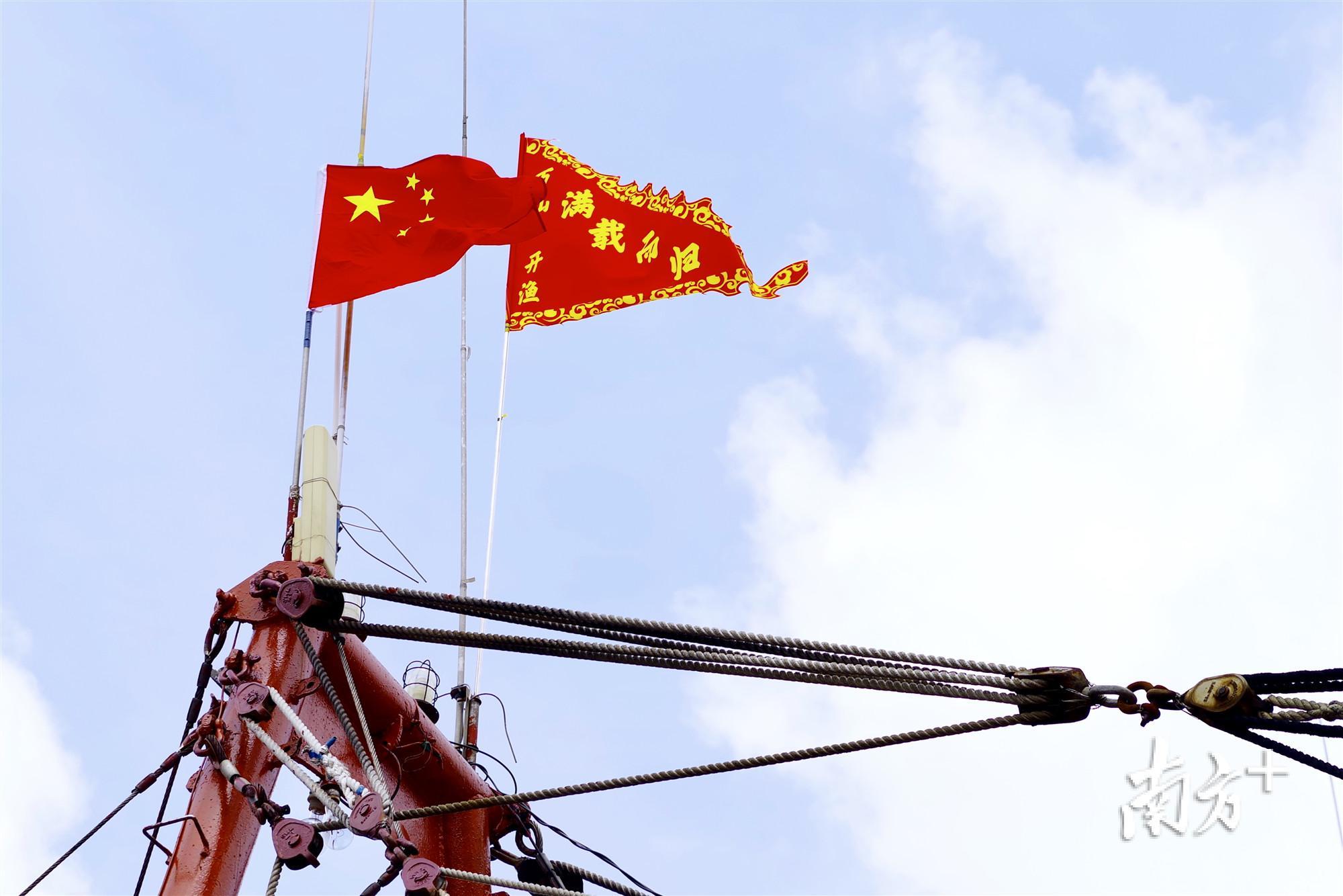 渔船出港前,渔民在船上升起五星红旗,以及分别书写着「满载而归」