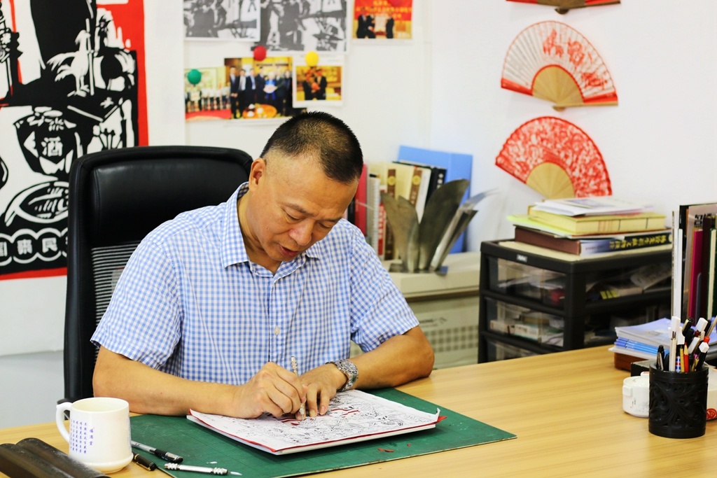 认真创作中的陈传生。身后挂着的多是他的剪纸作品。 认真创作中的陈传生。身后挂着的多是他的剪纸作品。