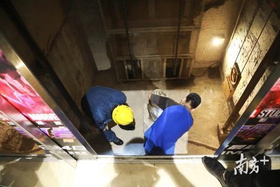 特检员赵磊钻入电梯底坑，检测液压缓冲器等设备。