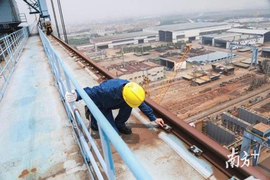 在中远船务一台高70多米、宽180米的龙门架上，特检员杨猛系上安全带，翻出防护栏，挨个检查龙门架边缘的螺丝有无松动。