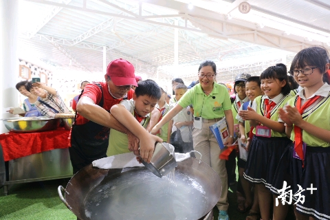 在活动现场，来自高明区富湾小学的学生们，跟着师傅一起学习濑粉的制作工艺。