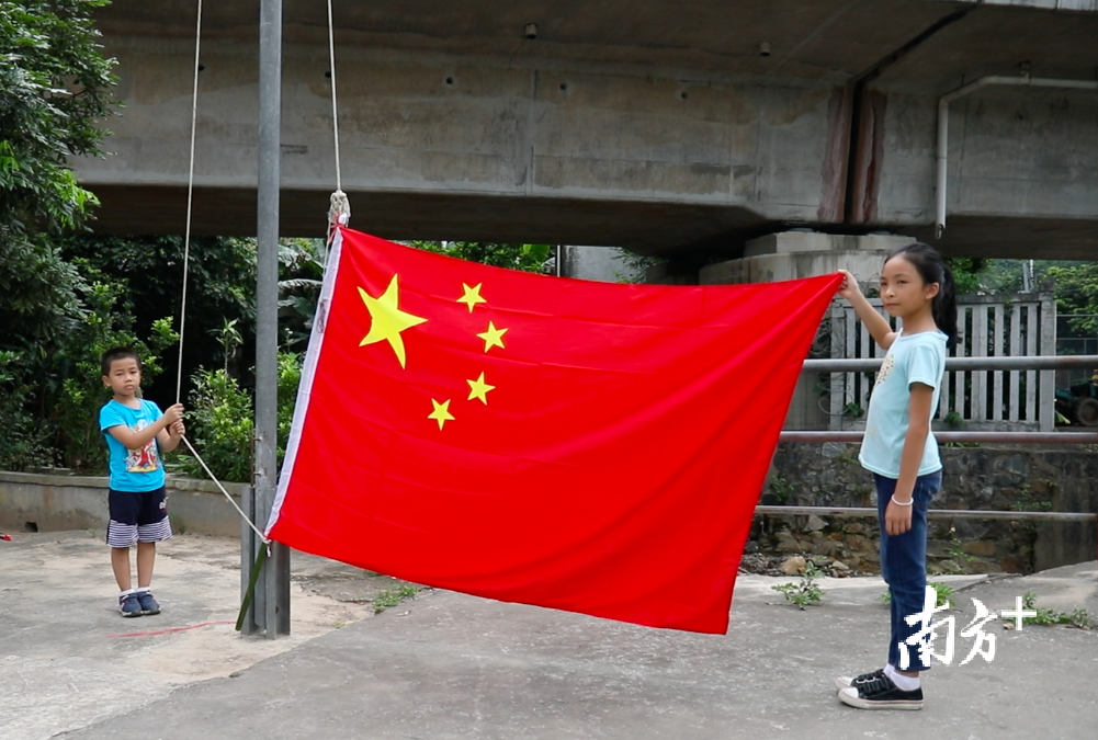 6岁的小旗手莫子谦肩扛比自己还高的五星红旗,迈着坚毅的步伐,缓缓