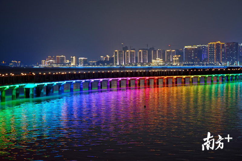在七彩灯光的渲染下，海上栈道如一道彩虹横跨海面。