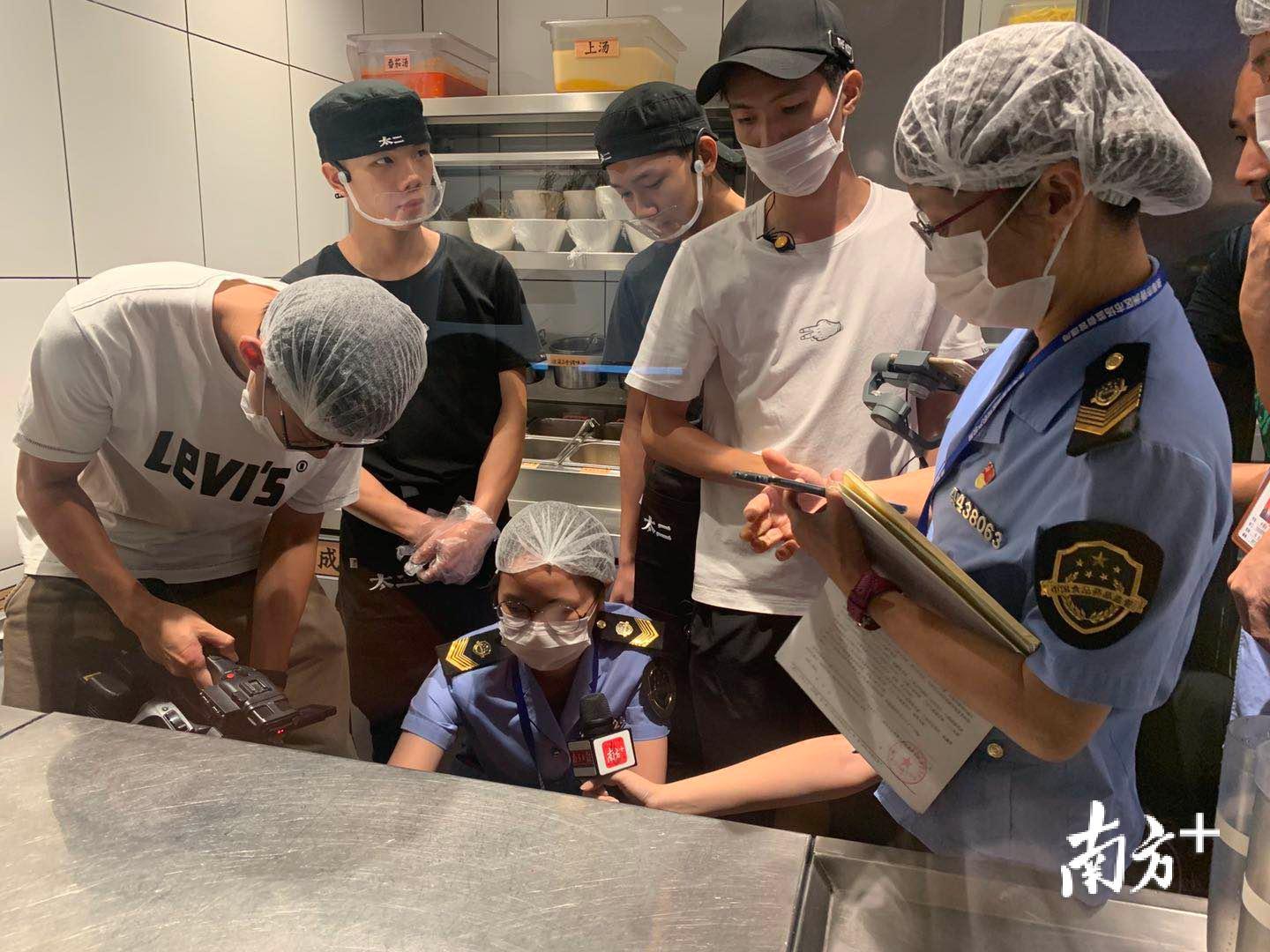 珠海市市场监督管理局的执法人员与南方+记者在太二酸菜鱼进行现场检查