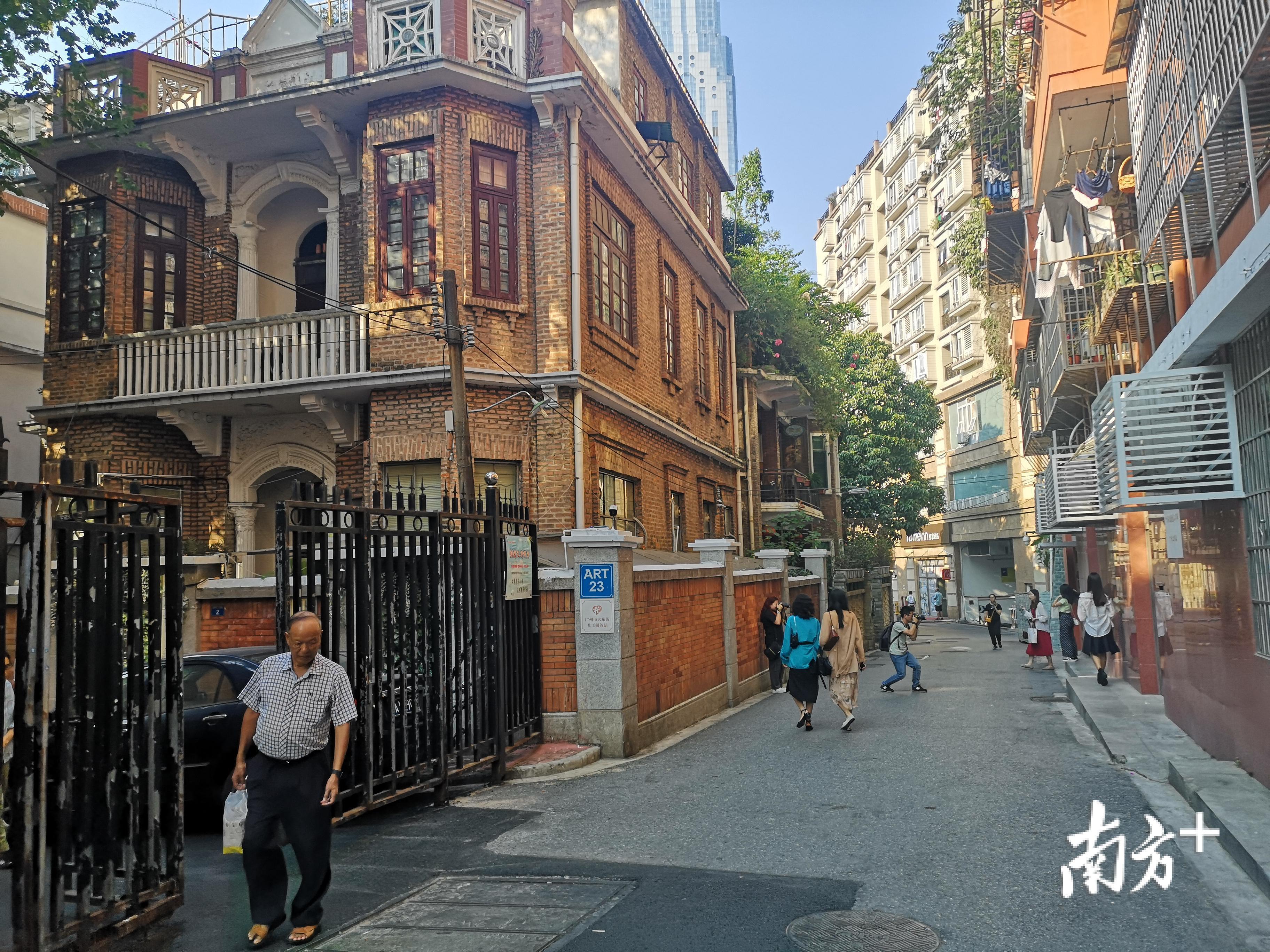 年轻人在东山口小洋楼前拍照，老居民擦肩而过。  黎詠芝 摄