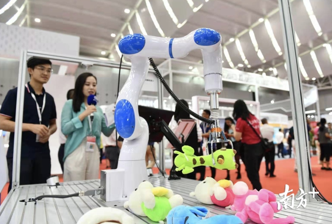 机器臂马上在桌面上摆放着6个娃娃中,识别出粉色的娃娃,并放下抓手