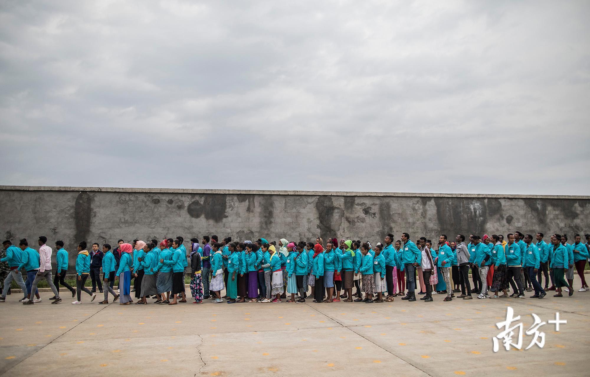 散会后,工人们排着队,等待进入厂房。 散会后,工人们排着队,等待进入厂房。