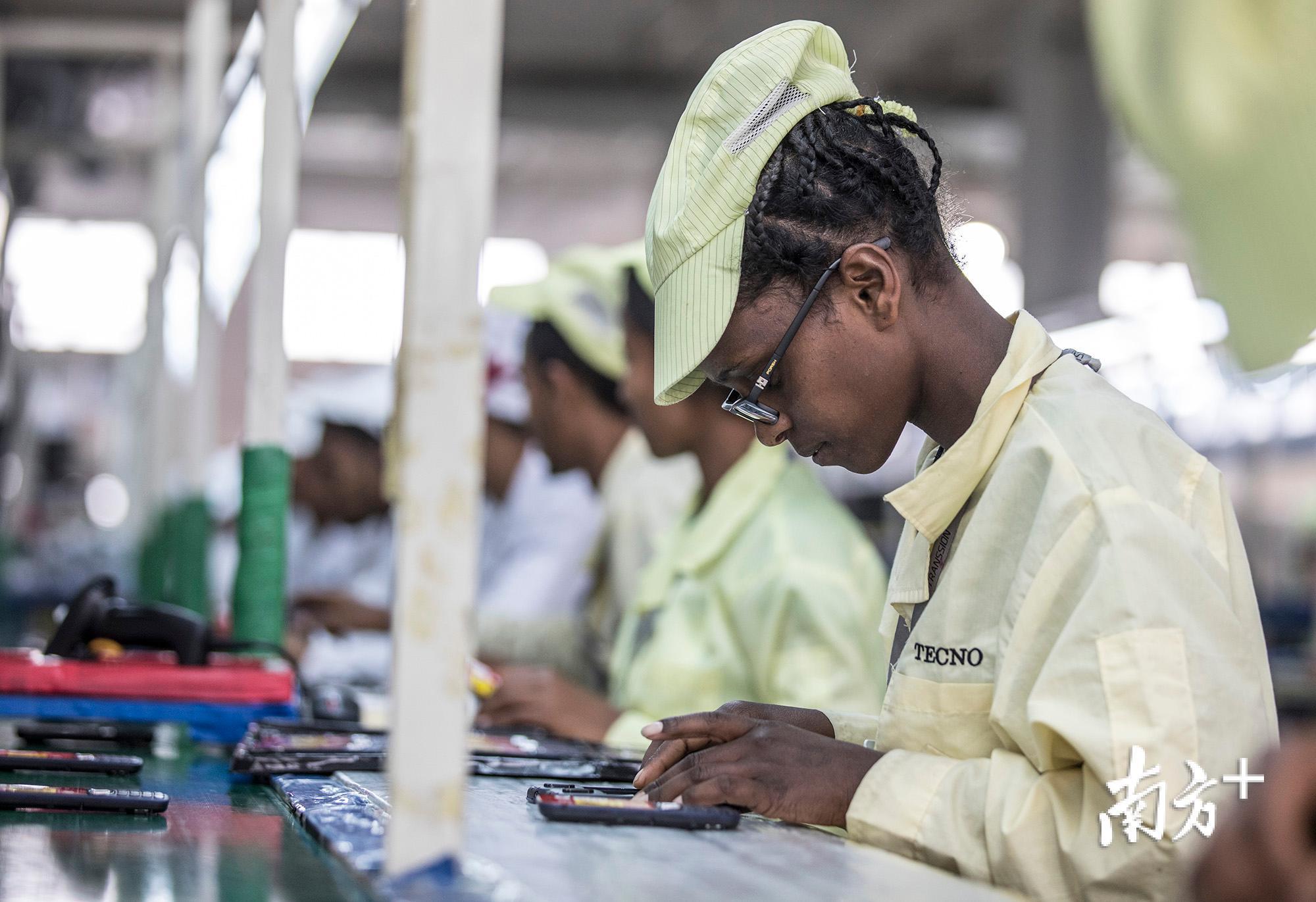 一名工人正认真地用电子元件组装一台手机。 一名工人正认真地用电子元件组装一台手机。