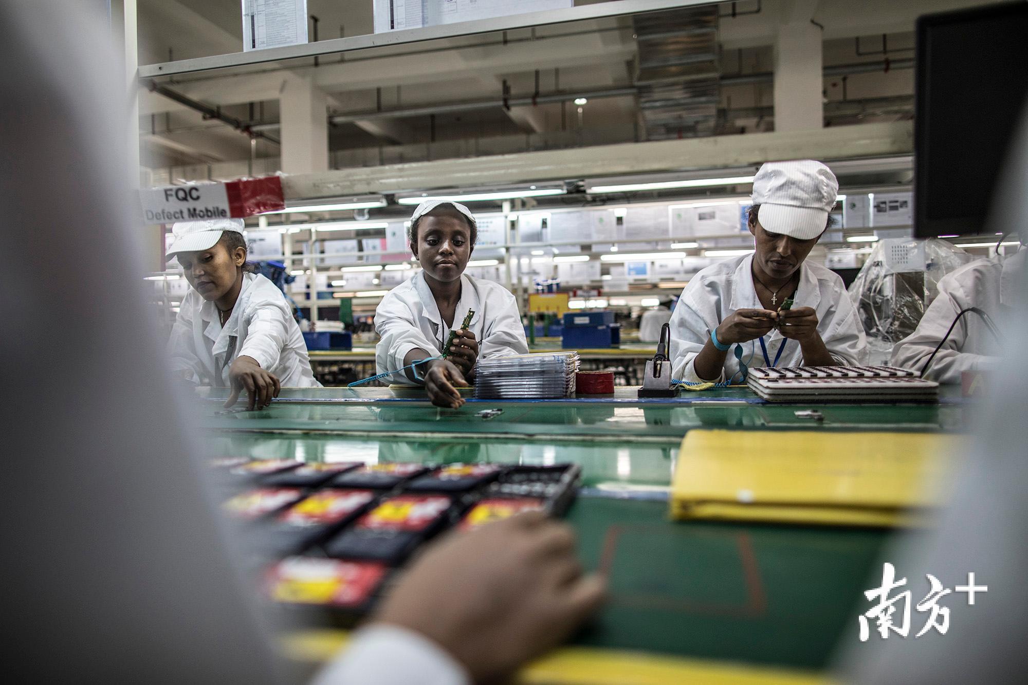 本地工人们正在流水线上组装手机零件。 本地工人们正在流水线上组装手机零件。