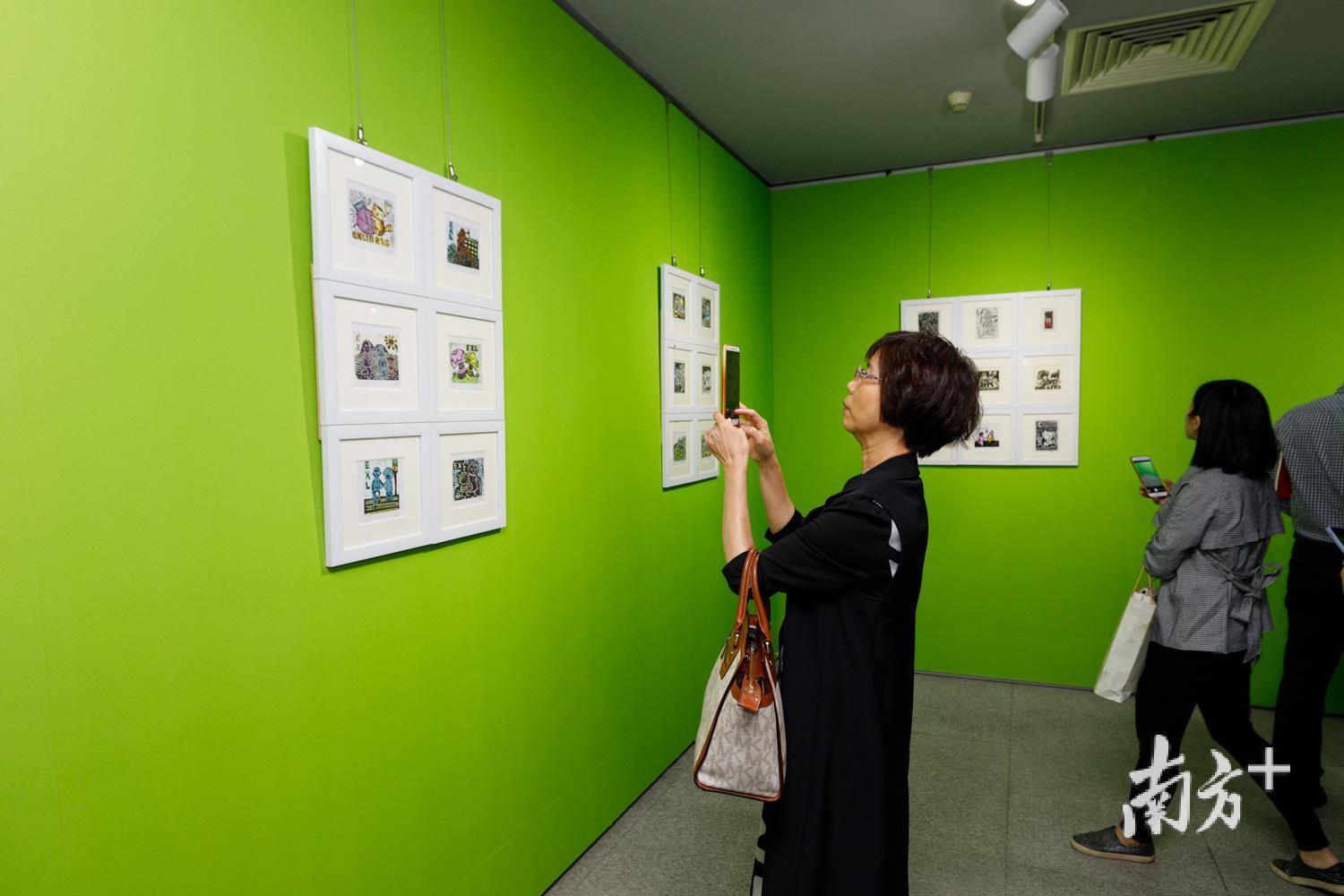 观众驻足欣赏藏书票作品。      余文诗摄