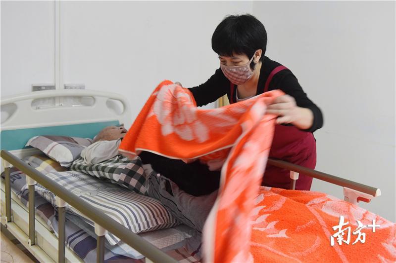 惠州市怡安养老院的护理员帮卧床老人擦洗完身子后盖好被子。