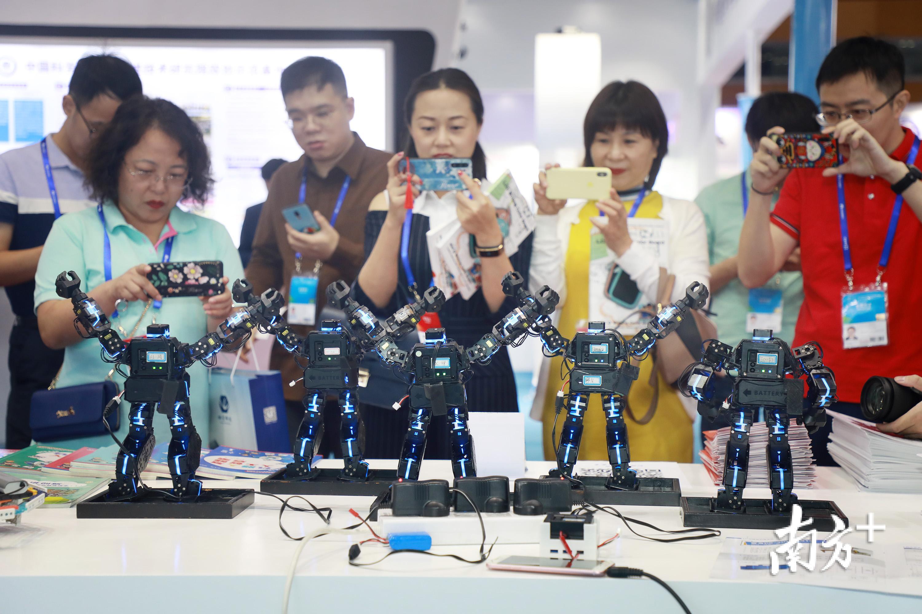 机器人载歌载舞迎宾，吸引观众围观。