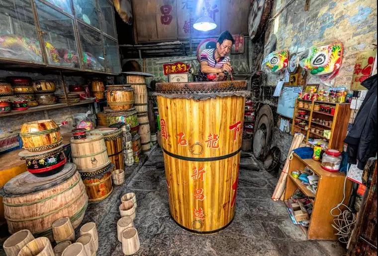 图为参展作品。有着百年历史的新昌鼓店坚持手工制鼓，远近闻名。蒙鼓皮的鼓机是一百多年前从德国定制。时光飞逝，鼓机闪着乌黑色的光泽，依旧还能蒙鼓皮制鼓。左图为叶浩和师傅正在为新制作的大鼓上色。Aleksandar Plavevski 摄（美国《国家地理》、欧新社签约摄影师）