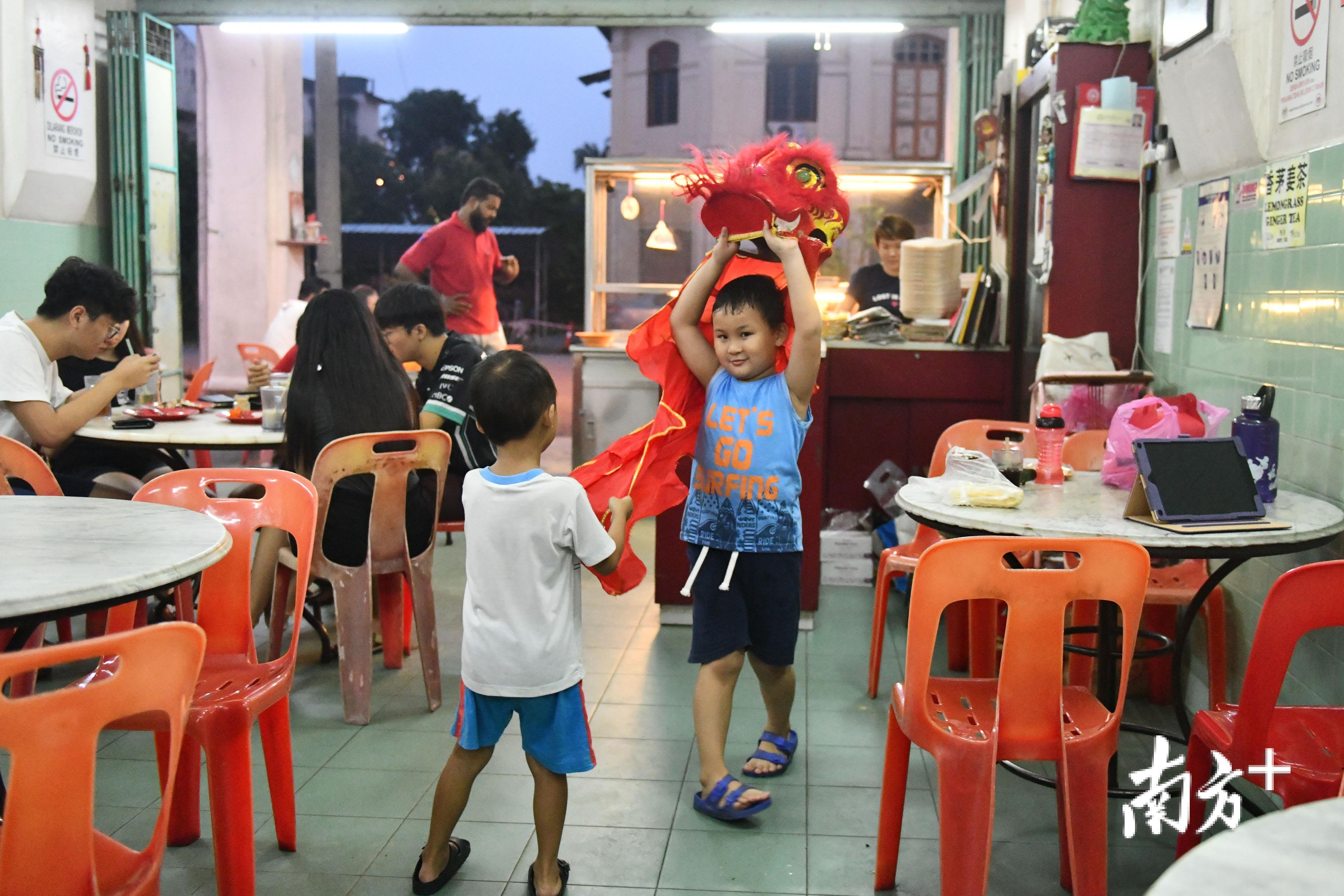 端洛的一家华人餐馆里，两个孩子手举着狮头在做着舞狮的动作。舞狮作为岭南文化的重要载体，在马来西亚得到了很好的传承。