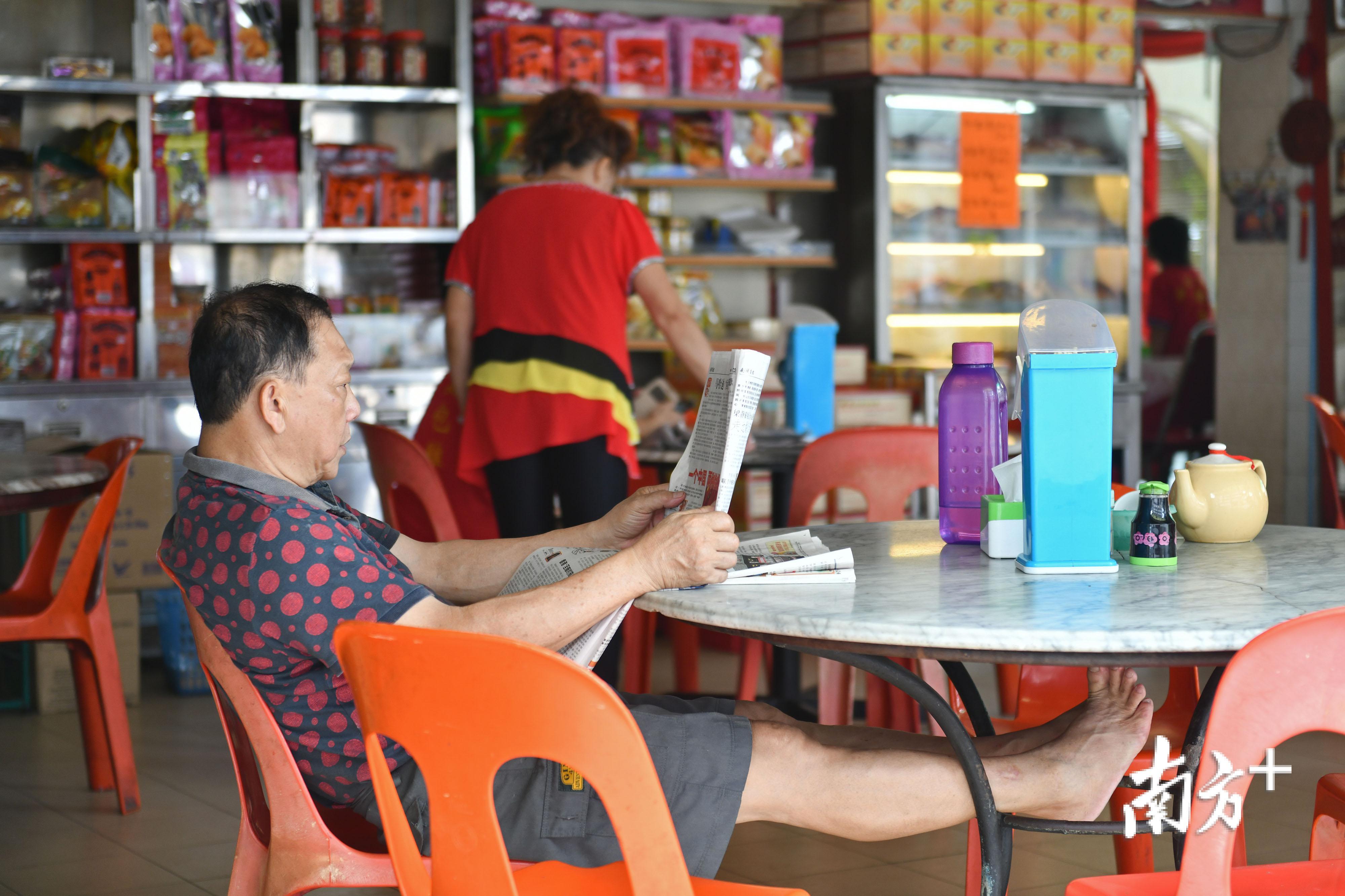 金宝街头，休闲地看着华文报纸的男子。