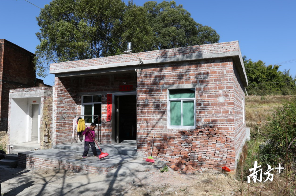 刘溅英欣喜地打扫新屋门前卫生。