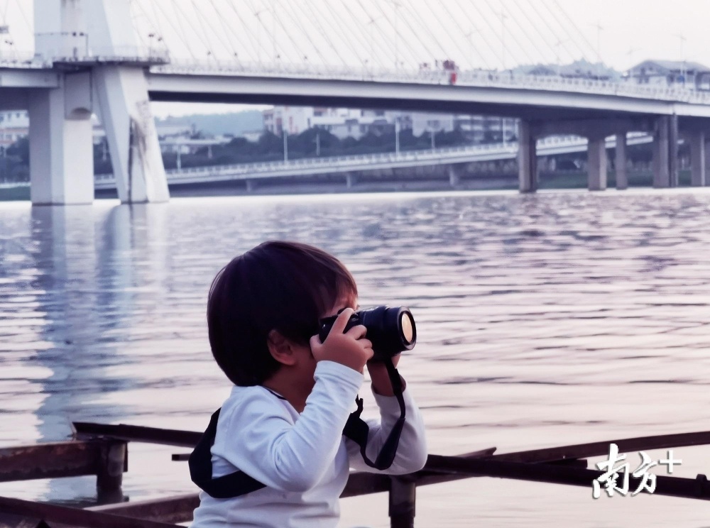 《十年后我与东江》。小女孩稚嫩的小手飞快按下快门，用她的视觉捕捉东江夕阳景色，而我捕捉的却是她童年东江里的回忆。（庄十三 摄）
