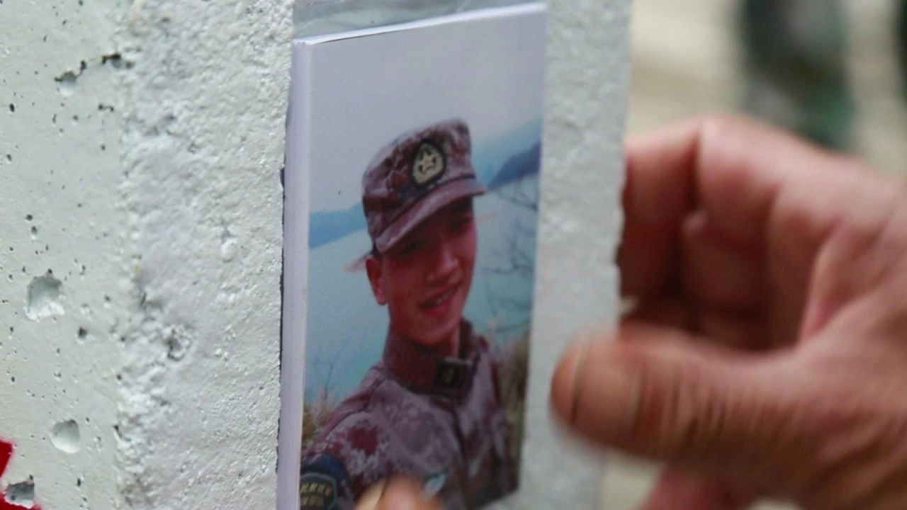 朱小华的父亲朱芳沅把儿子照片贴在碑石上。