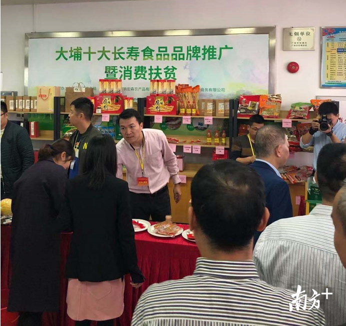 广东省电子商务协会副会长李华强向消费者介绍大埔长寿食品。