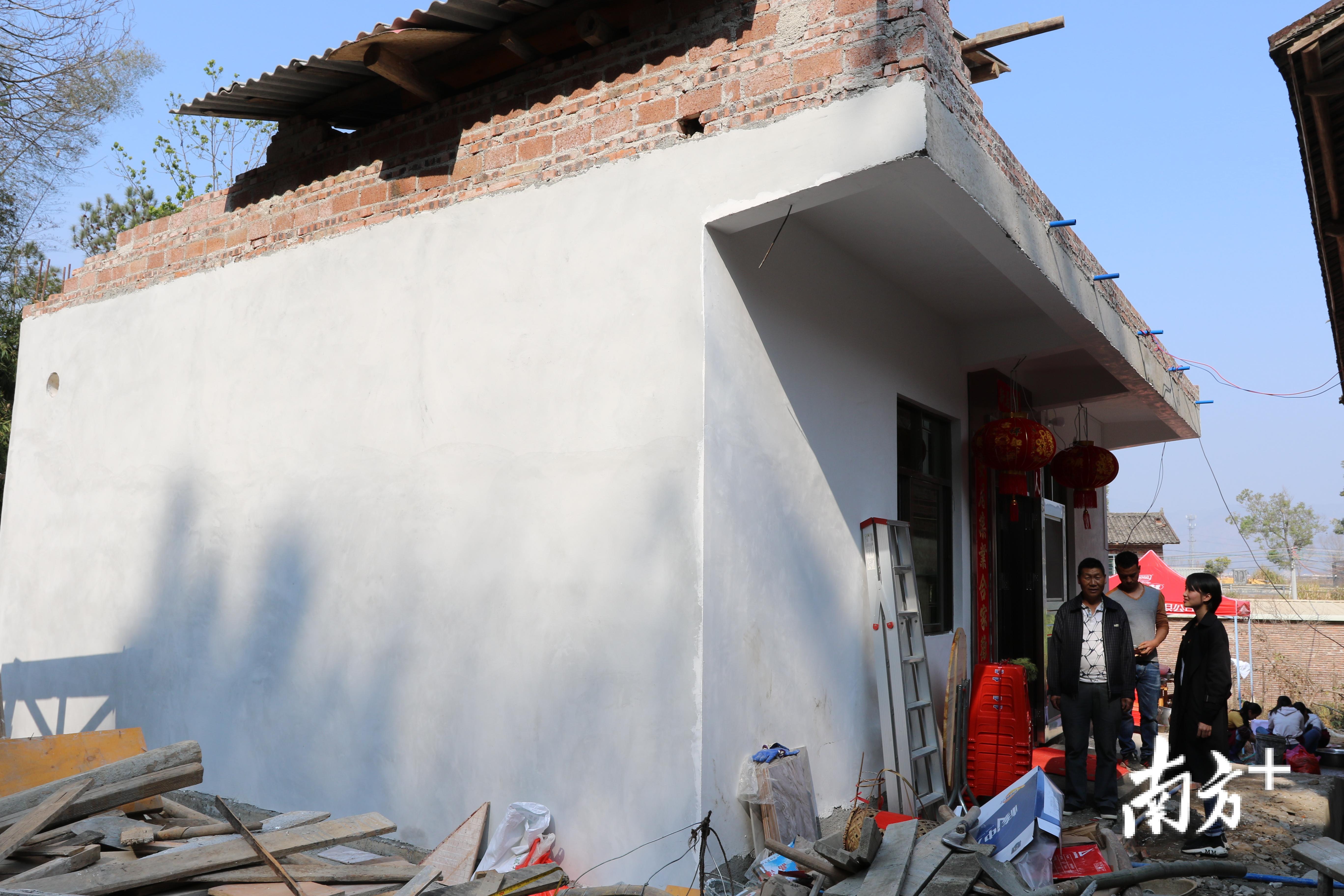 上坪镇副镇长何瑶瑶（右一）站在东阳村村民谢文捷（左一）新房门口，向谢文捷了解建房情况。