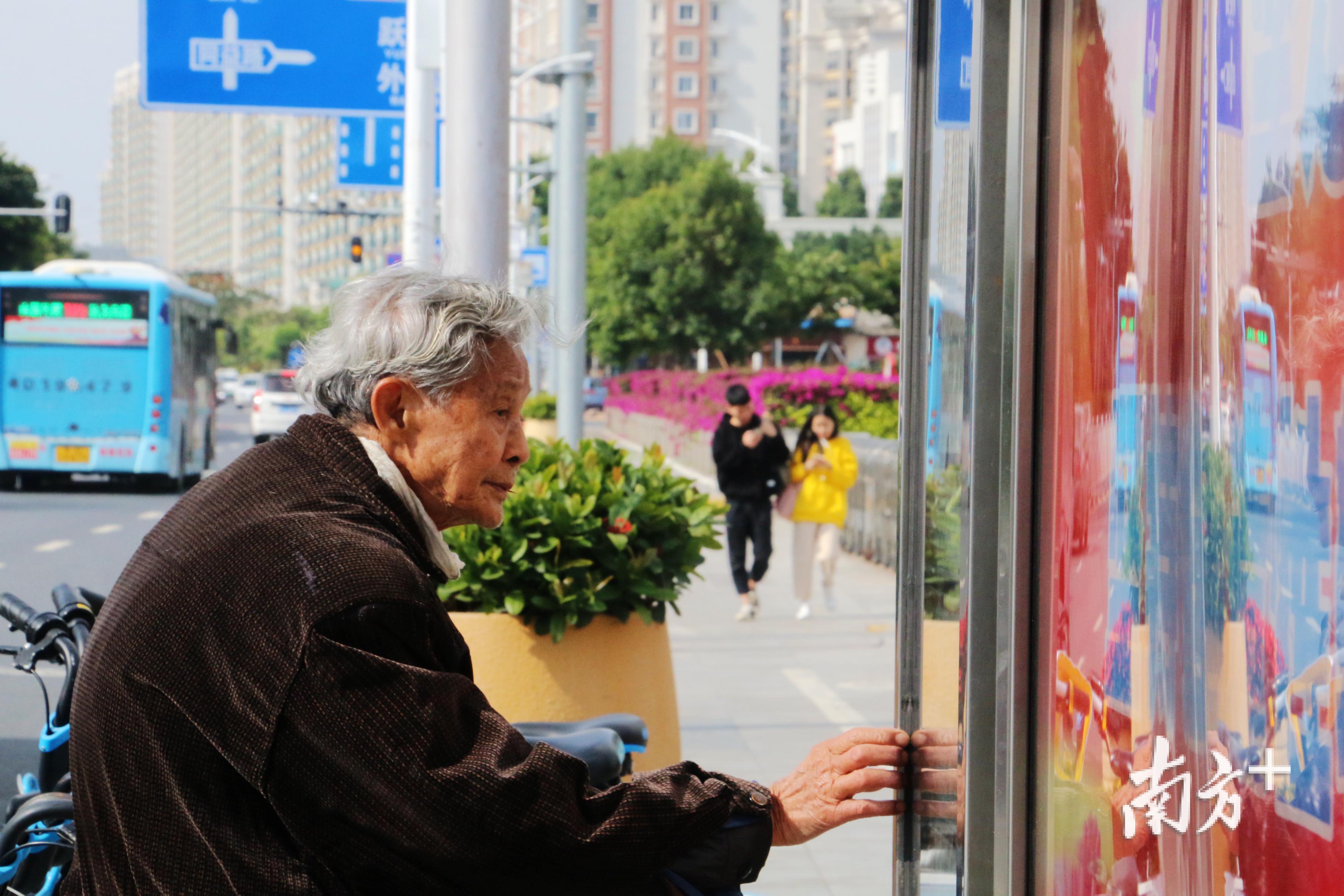 一名候车的老人在观看公交站牌上的公交车信息。