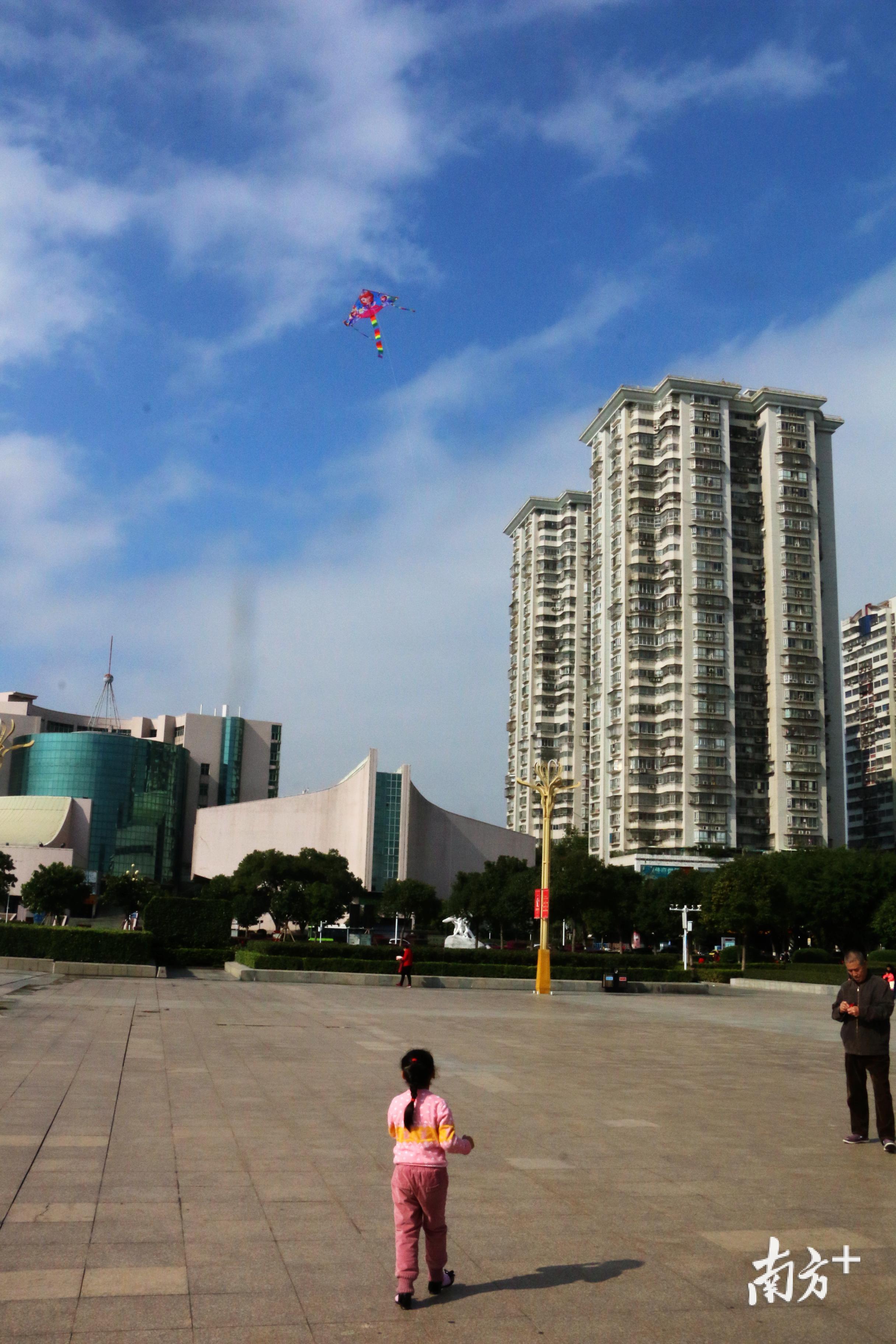 一名小女孩在爷爷的指导下放着风筝。