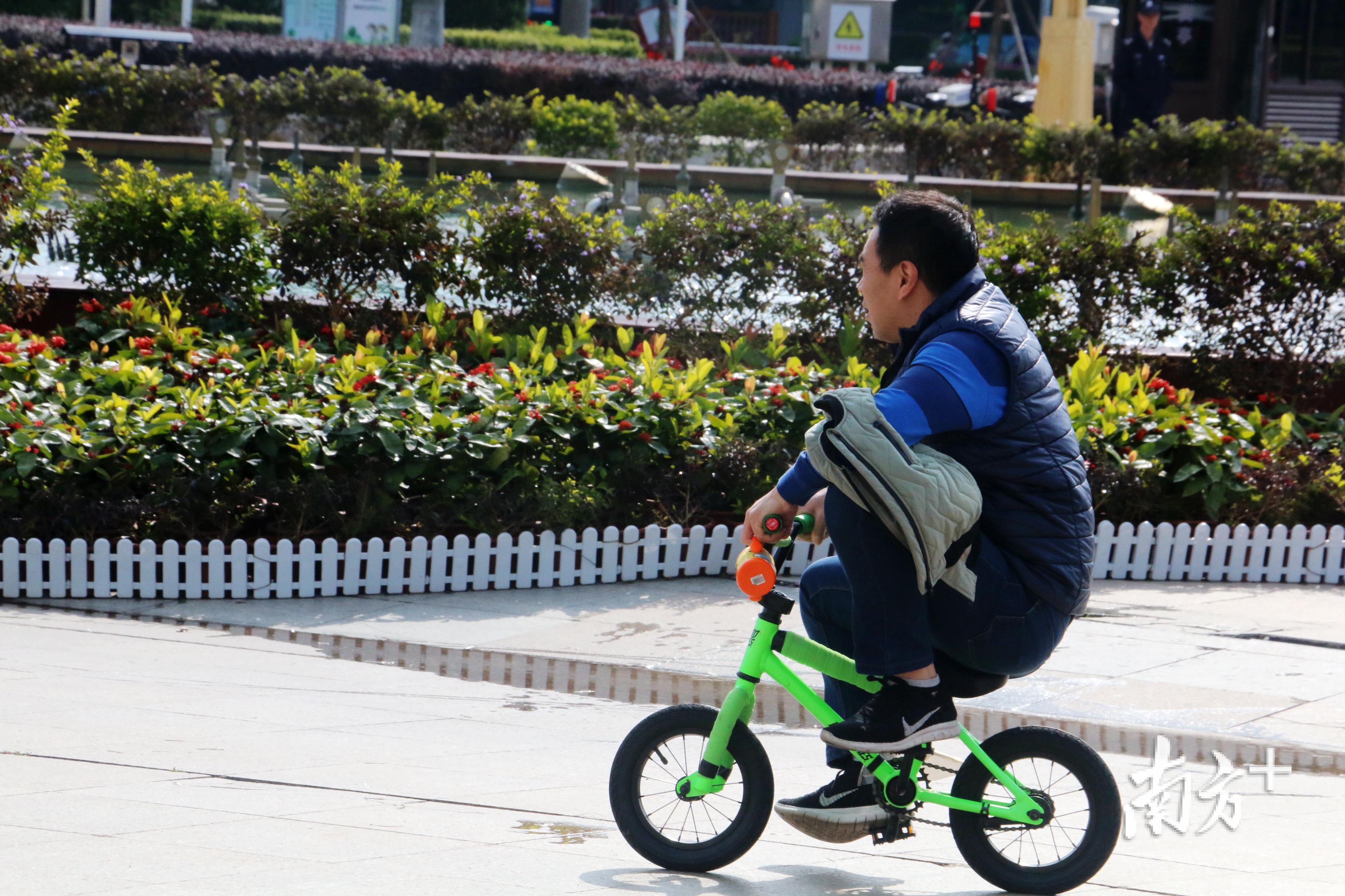 一名父亲向孩子示范骑车，乐在“骑”中。