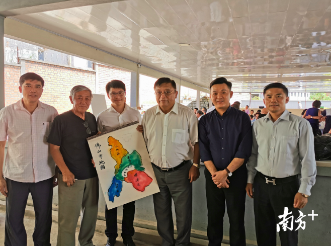 老华侨吴础禧（左二）现场手绘佛山五区的地图。田人心摄