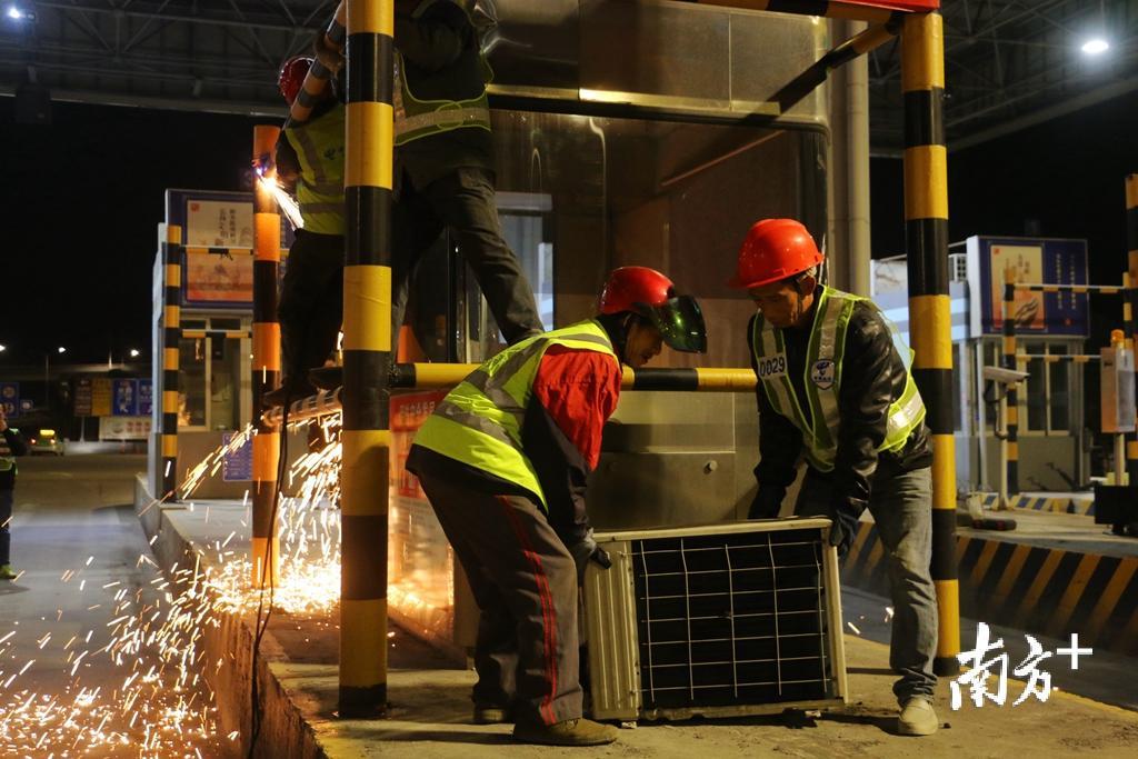 工作人员将收费亭的空调外挂机搬走。 工作人员将收费亭的空调外挂机搬走。