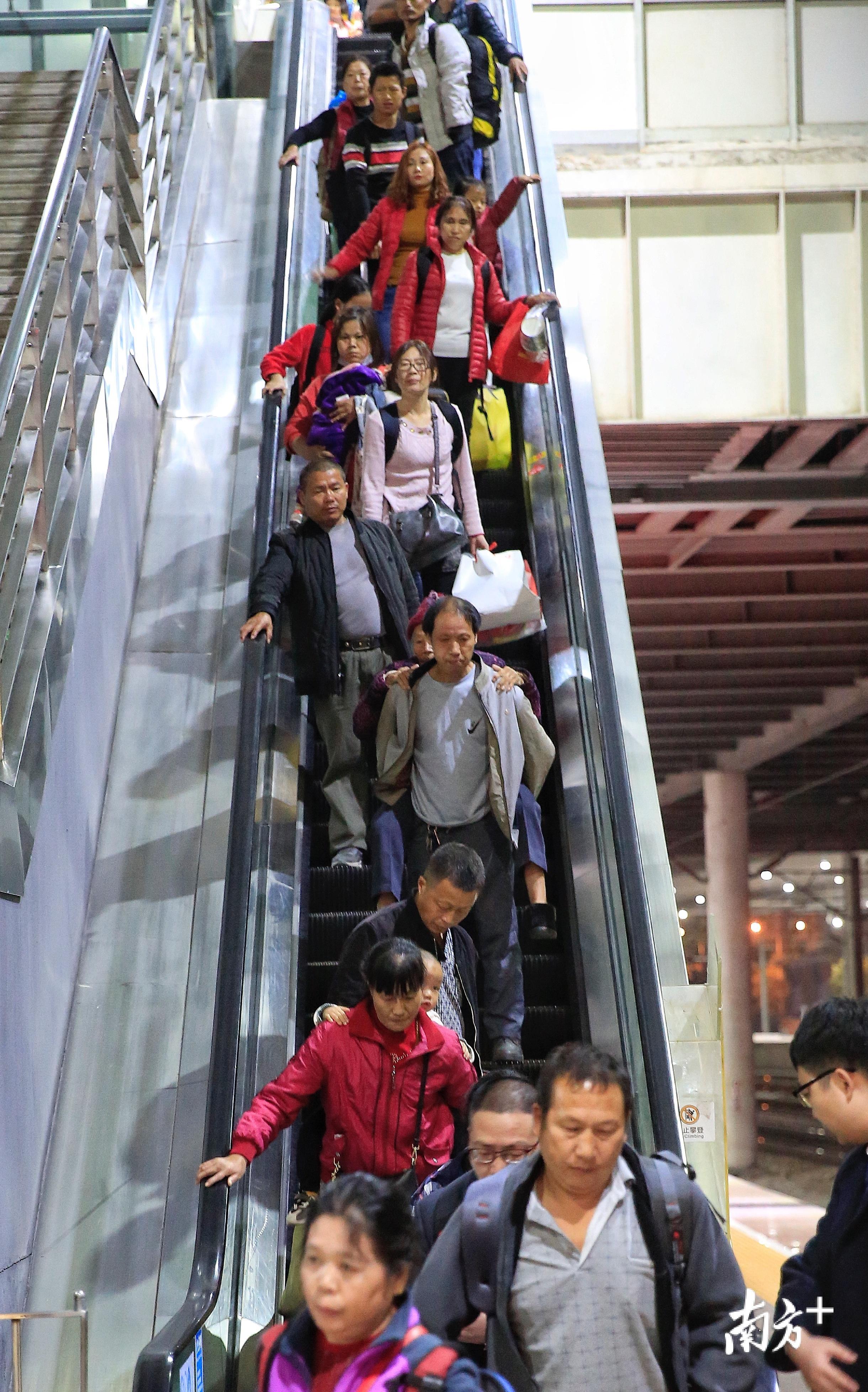 秦运林背着母亲乘坐手扶梯.早些时候,他的母亲不慎摔了一跤,腿脚不便.