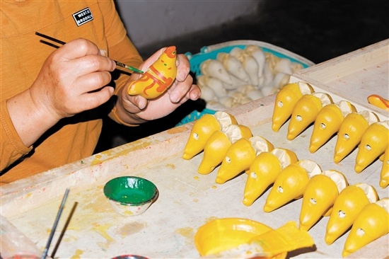 镇濠泥鸡最后一道制作工序——以彩漆勾勒图案。 镇濠泥鸡最后一道制作工序——以彩漆勾勒图案。