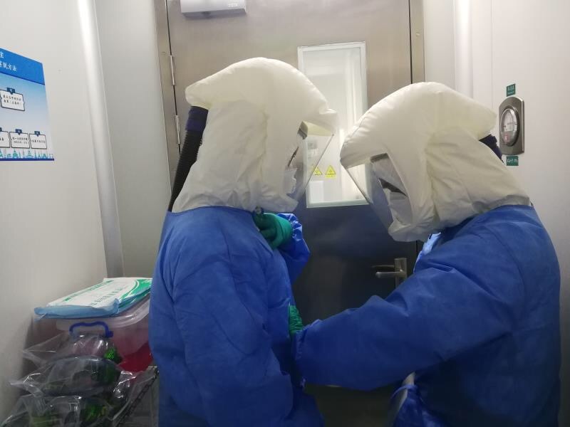 实验室正在进行确诊患者的病毒载量动态检测。他们在操作时穿着重达3-4斤的个人防护装备，进去一次就要连续工作4小时左右，每次出来内衣都全部湿透。