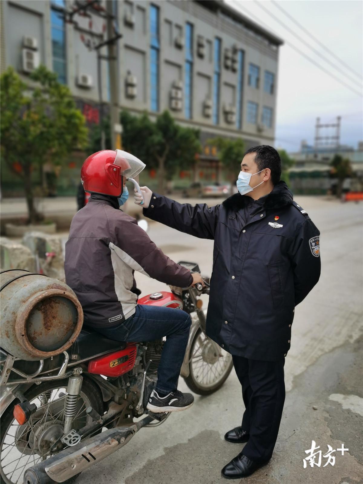 防疫工作队司法警察支队成员给摩托车驾驶员测体温 防疫工作队司法警察支队成员给摩托车驾驶员测体温