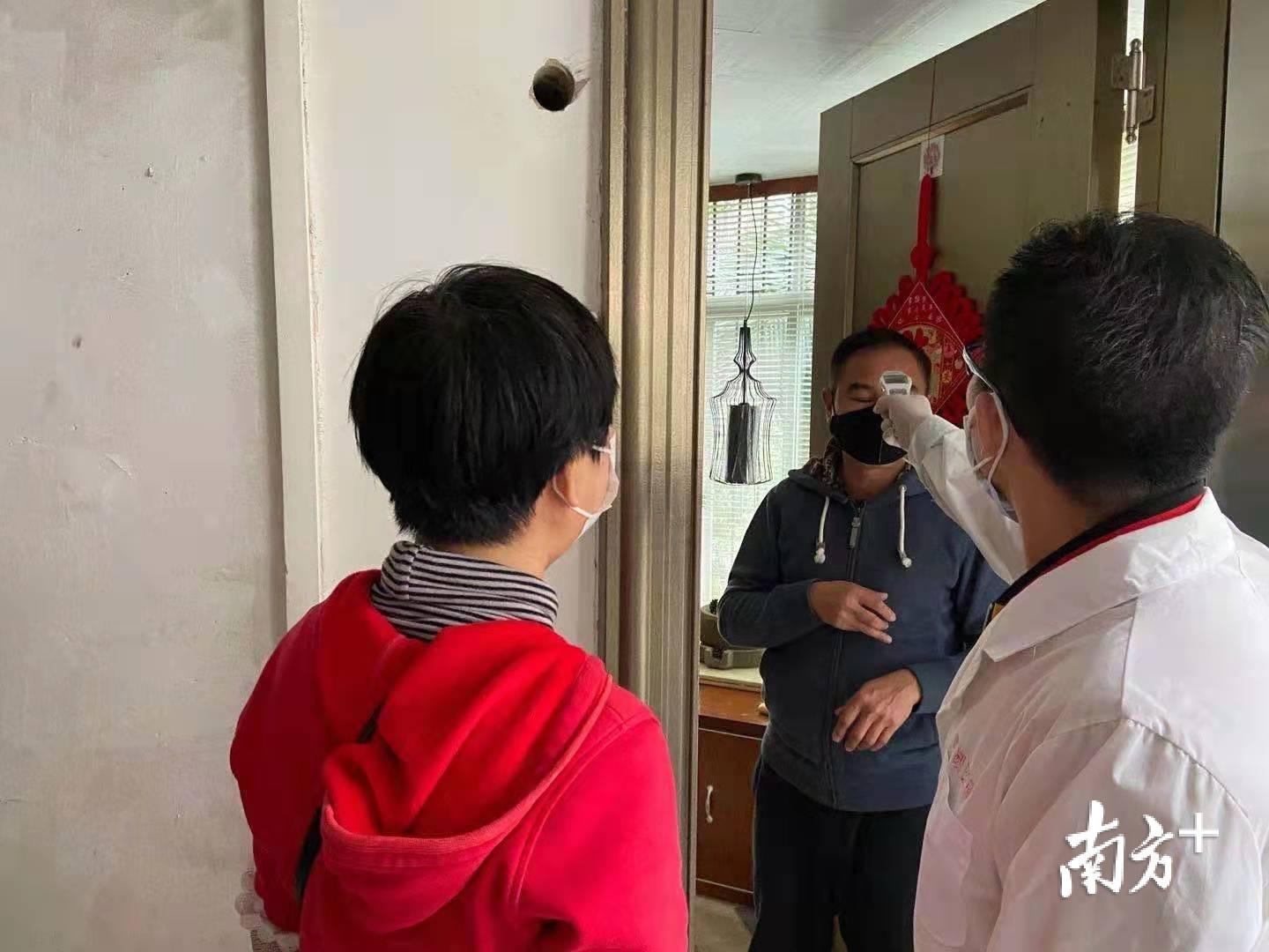 该区民享社区书记陈阳资和医务人员为居民量体温。