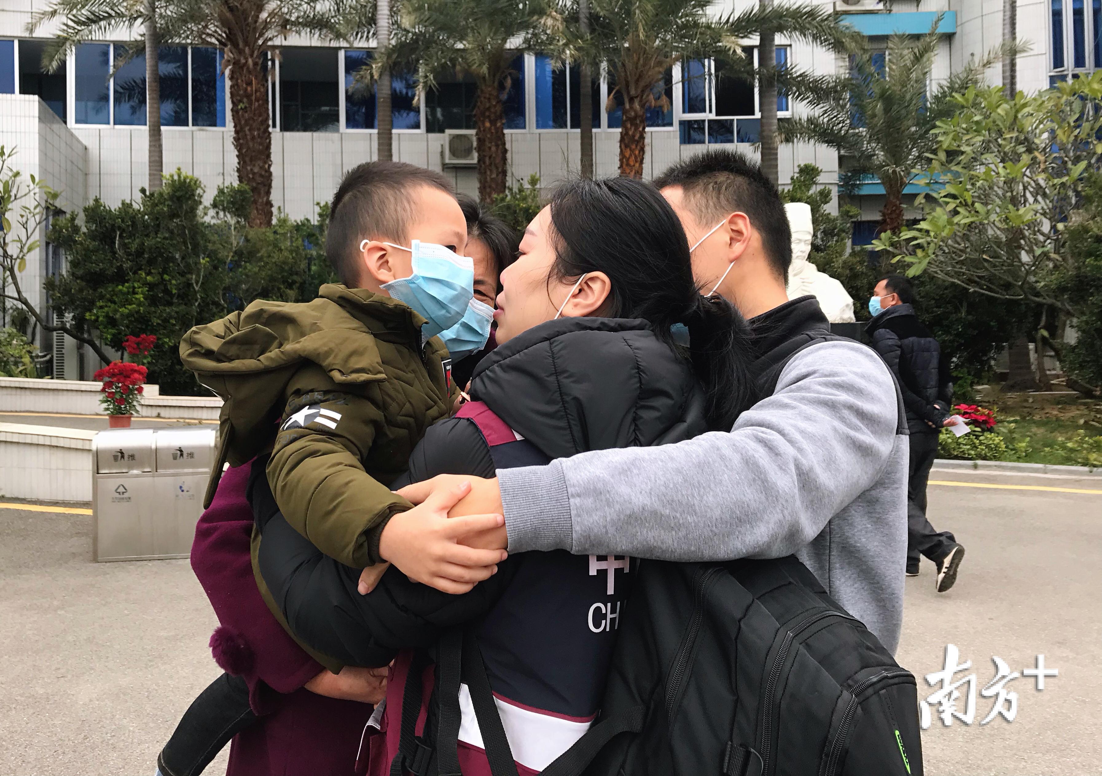 一家四口紧紧相拥，李琳摘下自己的口罩，轻吻戴着口罩的儿子诺诺。