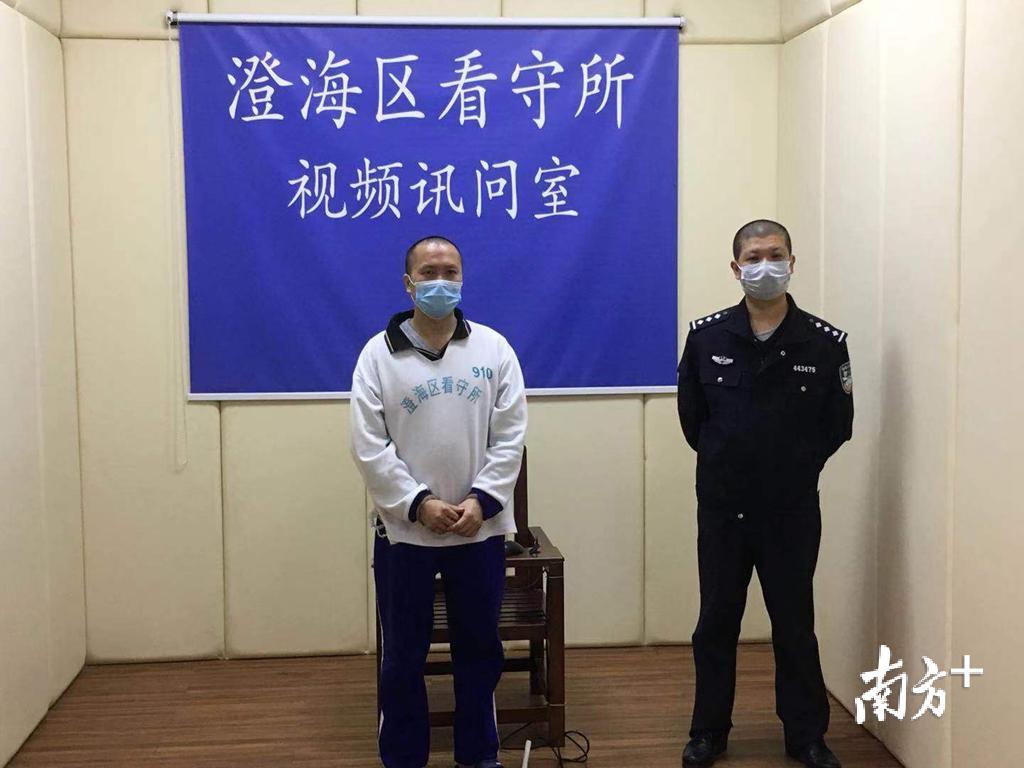 被告人在法警的看护下，面对屏幕参与庭审。