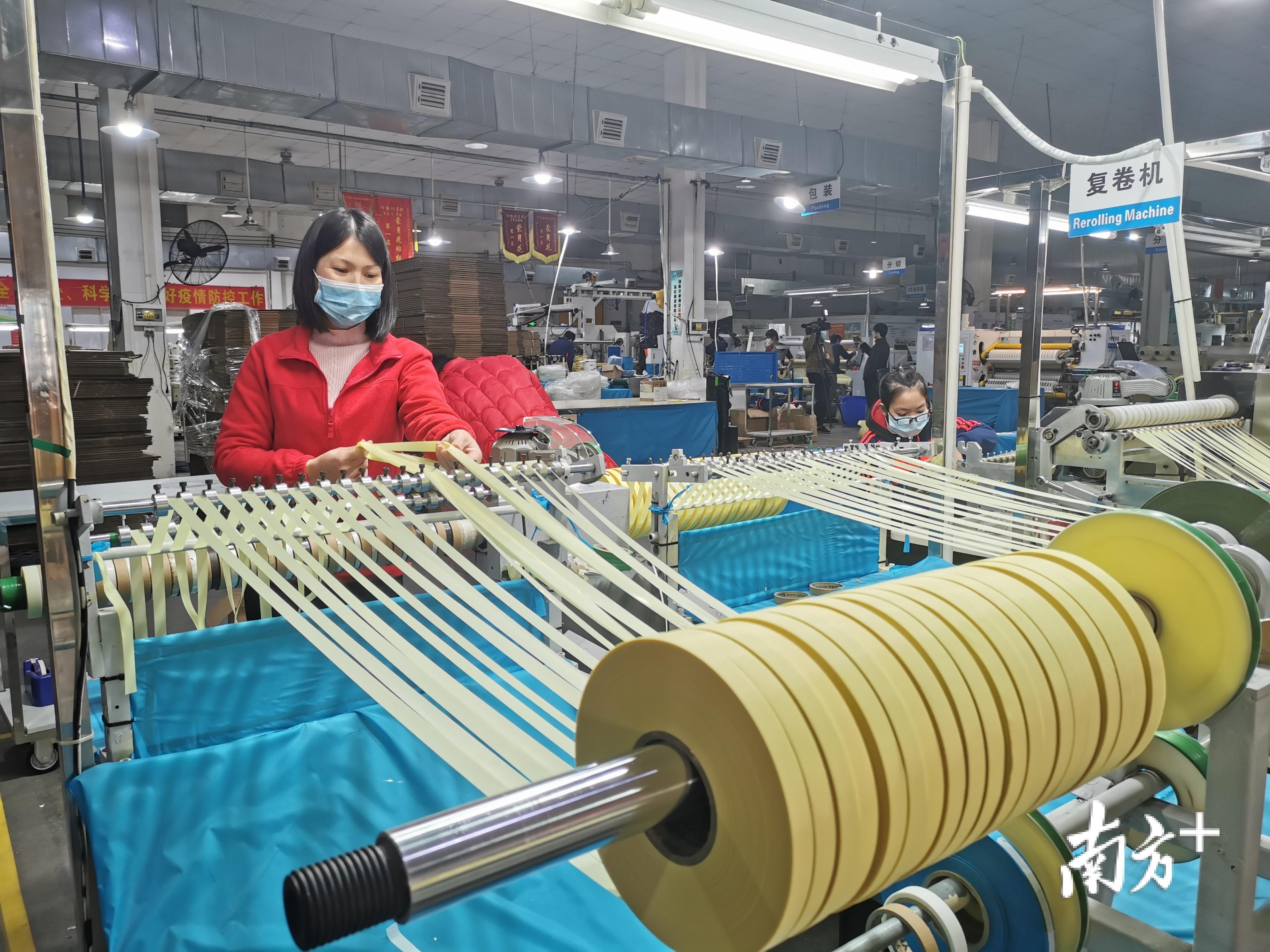 员工黄身静正在复卷机前检查产品。年初五时，身处广西老家的黄身静收到返岗通知，隔天就回到江门。黄身静说：“疫情这么严重，我也要为国家出一份力。”